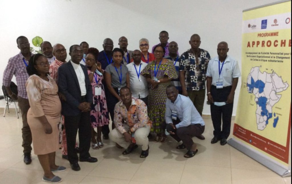 Les participants du programme APPROCHE posent à côté d'une banderole du programme montrant la carte de l'Afrique.