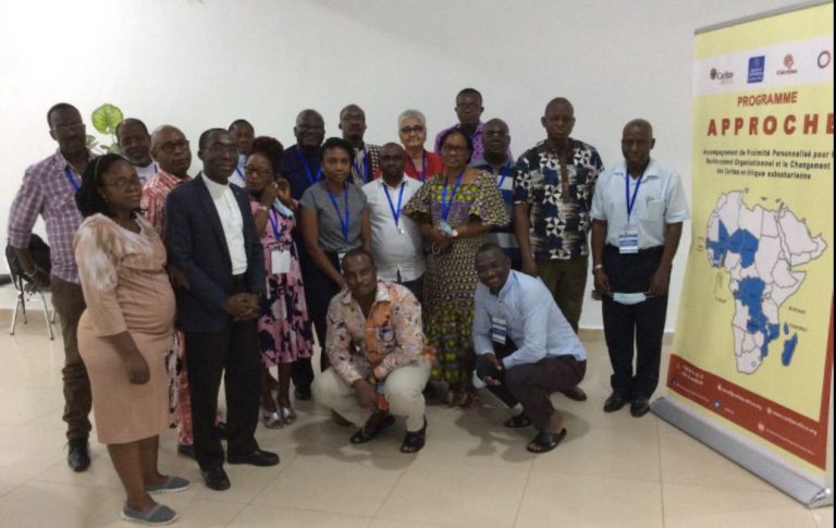 Les participants du programme APPROCHE posent à côté d'une banderole du programme montrant la carte de l'Afrique.