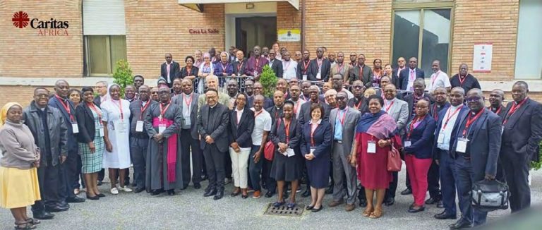Plusieurs dizaines de membres du réseau, évêques, religieuses et laïcs, posent devant un bâtiment portant le logo de Caritas Africa.